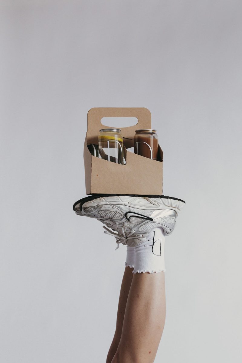 Daily Form Wellness branded glass jars in a carrier, resting on a sneaker
